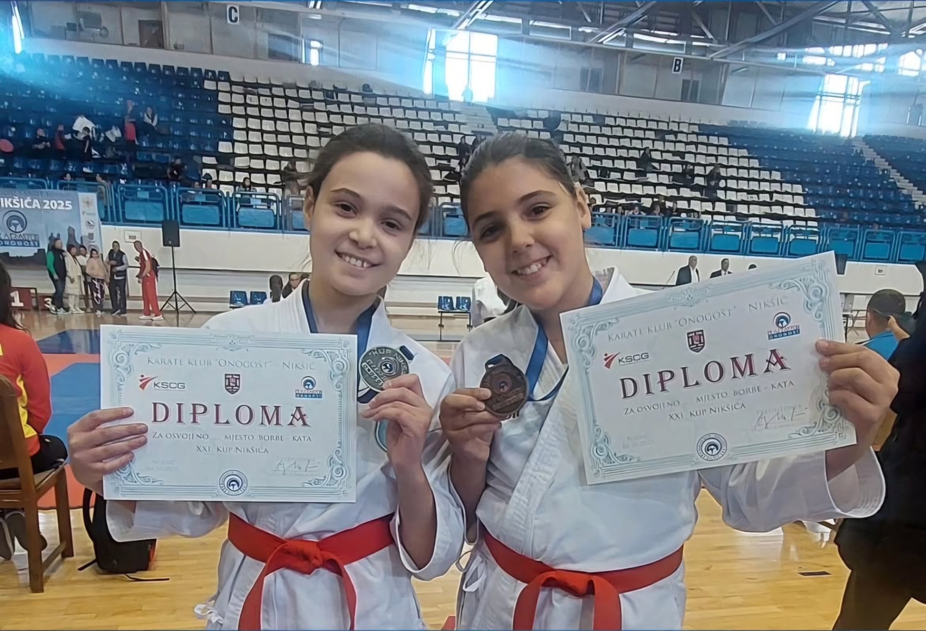 Two female competitors holding certificates together after a tournament