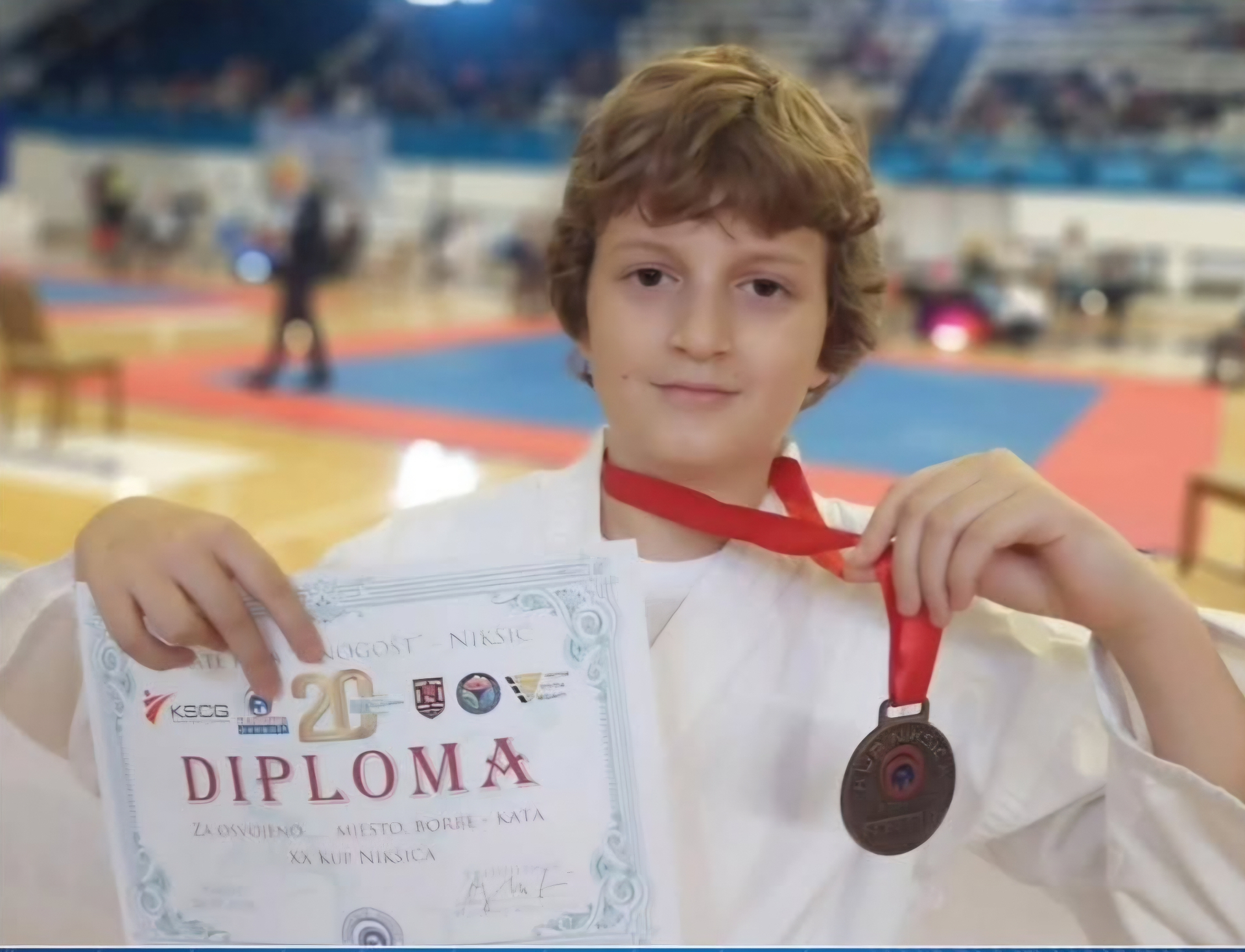A young competitor showing a certificate and a medal