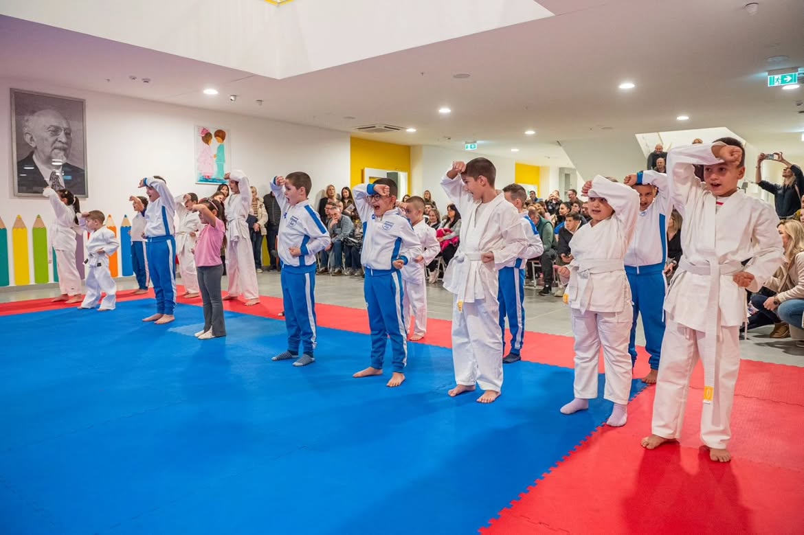 Club children demonstrating exercises on the tatami in front of an audience